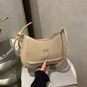 Minimalist beige leather shoulder bag with silver bow accent and knotted strap detail