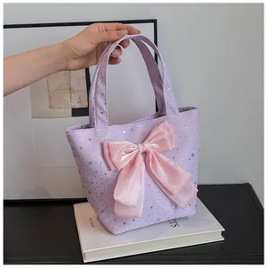 Detail of purple star tote bag featuring a large pink silk bow and shiny silver stars