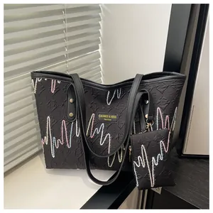Close-up of black tote bag with colorful wave embroidery and a mini matching pouch