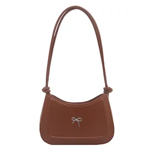 Brown faux leather shoulder bag with a silver metallic bow and knotted strap detail