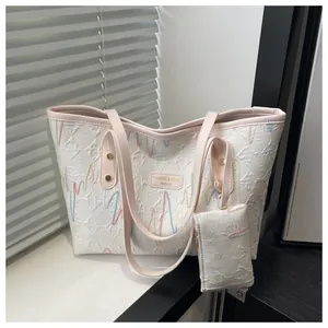 Detail of white tote bag with heart-rate embroidery and pink straps in soft lighting