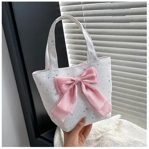 Detail of white canvas tote with silver star sequins and a large pink satin bow