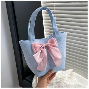 Detail of light blue handbag with a pink satin bow and silver star patterns