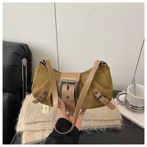 Détail du sac sous l'aisselle en daim moutarde vintage avec boucle en métal et cuir marron