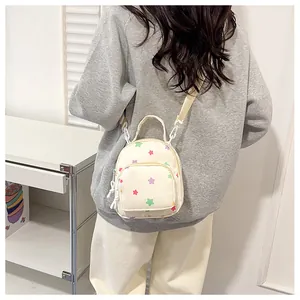 Dettaglio mini zaino color crema con motivi a stelle colorate e spalline in tessuto