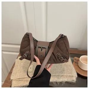 Détail du sac à bandoulière en daim marron vintage avec une grande boucle métallique décorative