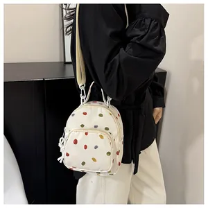 Dettaglio del mini zaino in tela con pois colorati e tasca anteriore con cerniera