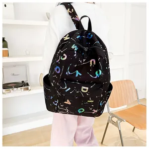 Close-up of black canvas backpack featuring colorful holographic letters and splatter prints