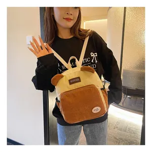 Detail of a corduroy backpack in beige and brown featuring cute patches and soft texture