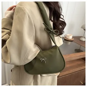 Detalle del bolso de hombro verde oliva con hebilla de mariposa plateada y adornos de lazos