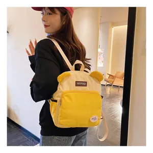 Detail of a corduroy backpack featuring cute bear ears and a contrasting yellow color design