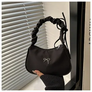 Detalle de bolso media luna negro con lazo de mariposa plateado y asa fruncida chic
