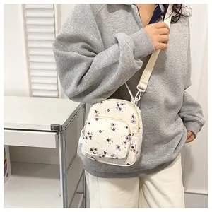 Dettaglio mini zaino in tela floreale con motivo a fiori viola e tasca frontale zip