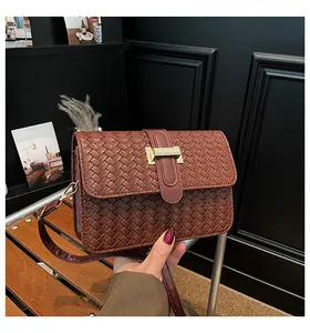 Detail of dark brown woven texture handbag with a rectangular gold metal clasp