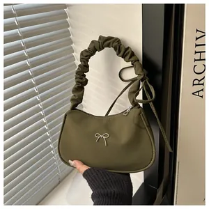 Detalle del bolso de tela verde oliva con asa fruncida y mariposa plateada
