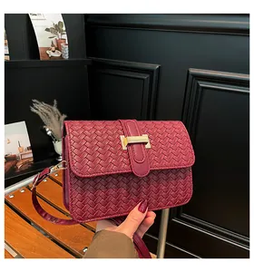 Detail of burgundy woven leather bag featuring a gold rectangular metal buckle