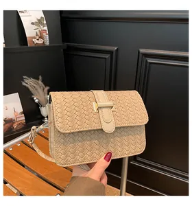 Detail of beige woven texture square crossbody bag with gold metal buckle closure