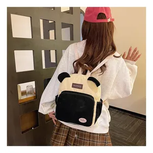 Detail view of a corduroy panda backpack with cute black ears and decorative patches