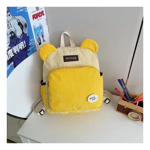 Close-up of yellow corduroy backpack featuring bear ears and leather brand label detail
