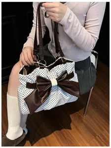Detail of polka dot tote bag with large brown leather bow and delicate lace trim