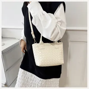 Detail of minimalist woven cream tote bag with gold metal hardware and adjustable strap