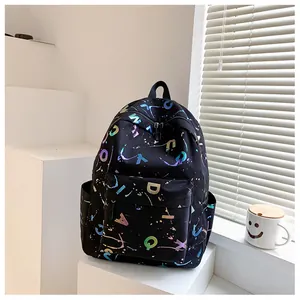 Detail of black backpack with colorful letter prints and front zipper pocket on white stairs