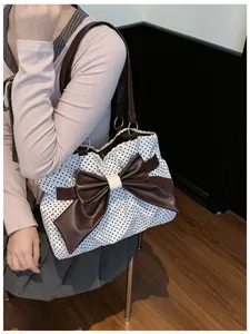 Detailed view of polka dot tote bag with lace trim and large brown decorative bow