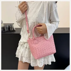 Detail of pink woven handbag featuring square weaving pattern and gold metal buckles