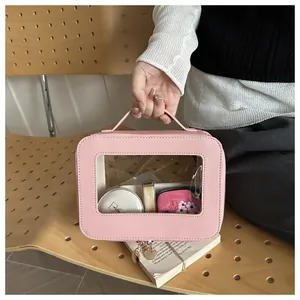 Beauty case rosa con finestra trasparente e cerniera dorata su una panca in legno