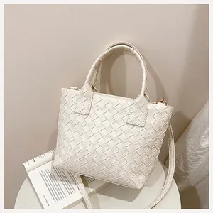 Close-up of woven cream bucket bag texture with sturdy handles and slim shoulder strap