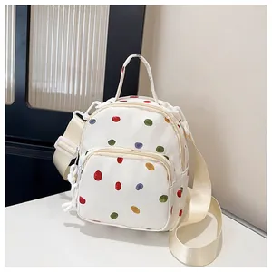 Dettaglio mini zaino in tela con pois colorati e tasca frontale con cerniera