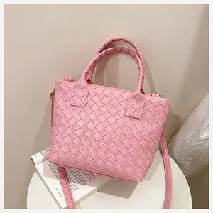 Detailed macro view of pink woven leather tote with gold hardware and shoulder strap