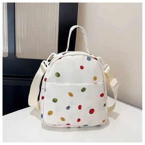 Dettaglio del mini zaino in tela beige a pois colorati con spallacci regolabili