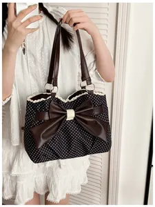 Close-up of black polka dot tote bag featuring a brown leather bow and lace trim detail