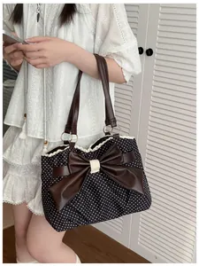 Close-up of polka dot tote bag featuring a brown leather bow and delicate lace trim detail