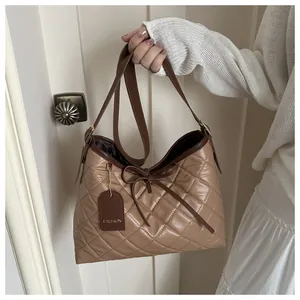 Detail of vintage tote bag featuring quilted leather patterns and brown bow ribbon decor