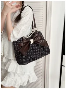 Polka dot tote bag with large bow and lace trim detail worn by model for scale
