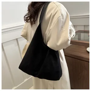 Detail of a large black tote bag on a model in a beige coat for a casual city look