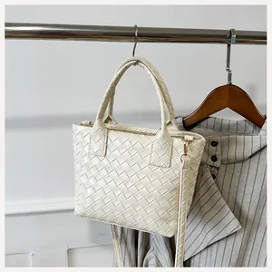 Detailed view of the off-white woven tote bag with adjustable shoulder strap