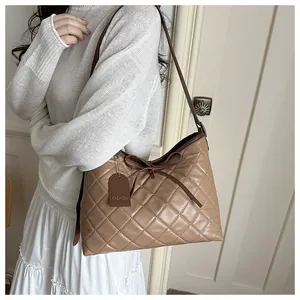 Detail of khaki quilted tote bag featuring a decorative bow and fashion tag