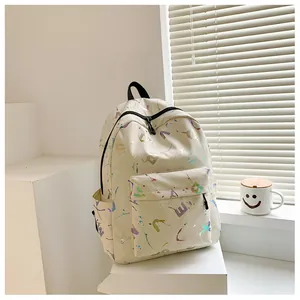 Detail of cream backpack featuring holographic letter prints and colorful ink splashes