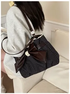 Close-up of polka dot tote bag with a large brown leather bow and lace edge trim detail