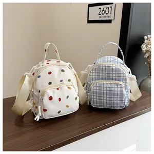 Dettaglio di mini zaini in nylon con motivi a pois e quadretti e tracolla in tessuto