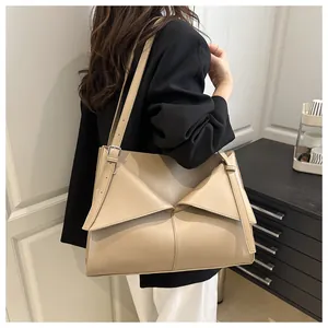 Détail d'un grand sac cabas beige avec un design croisé en cuir et une texture mate