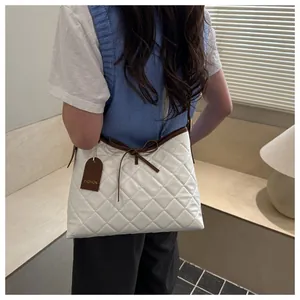 Close-up of quilted tote bag featuring a brown leather bow and fashion tag detail
