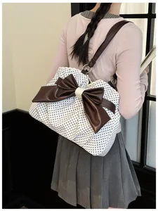 Detailed side view of polka dot tote bag with large brown bow and lace trim on a model
