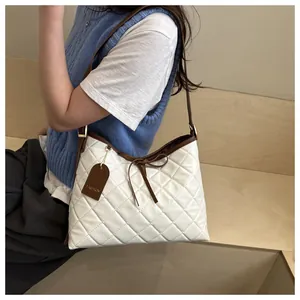 Detail view of quilted cream tote bag with brown trim and delicate bow knot decoration