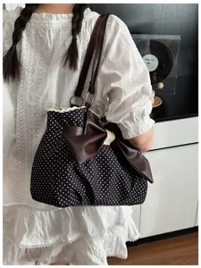 Close-up of polka dot tote bag featuring white lace trim and large brown bow detail