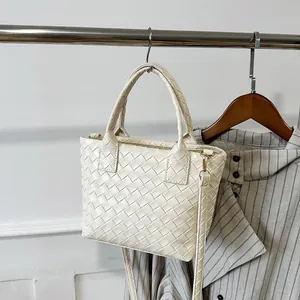 Chic cream woven basket bag with dual handles and gold hardware in a home setting