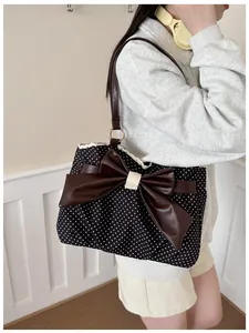 Close-up of polka dot tote bag with brown leather bow and delicate white lace trim
